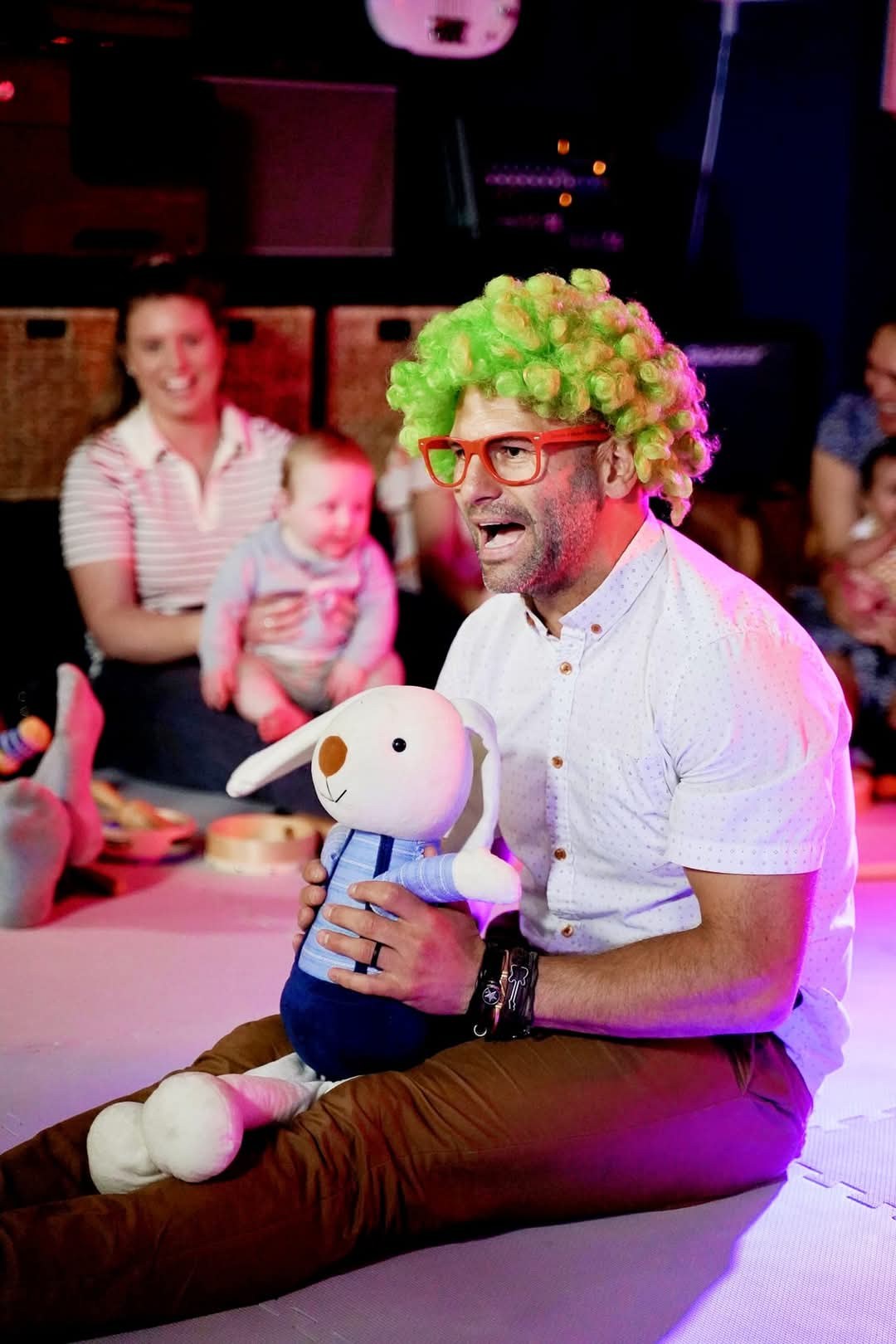 Barry de Jager singing and playing with a puppet while a parent and baby look on