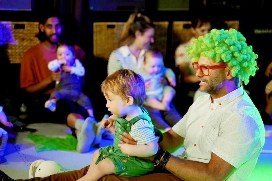 Barry making music with parents and babies in a bright room
