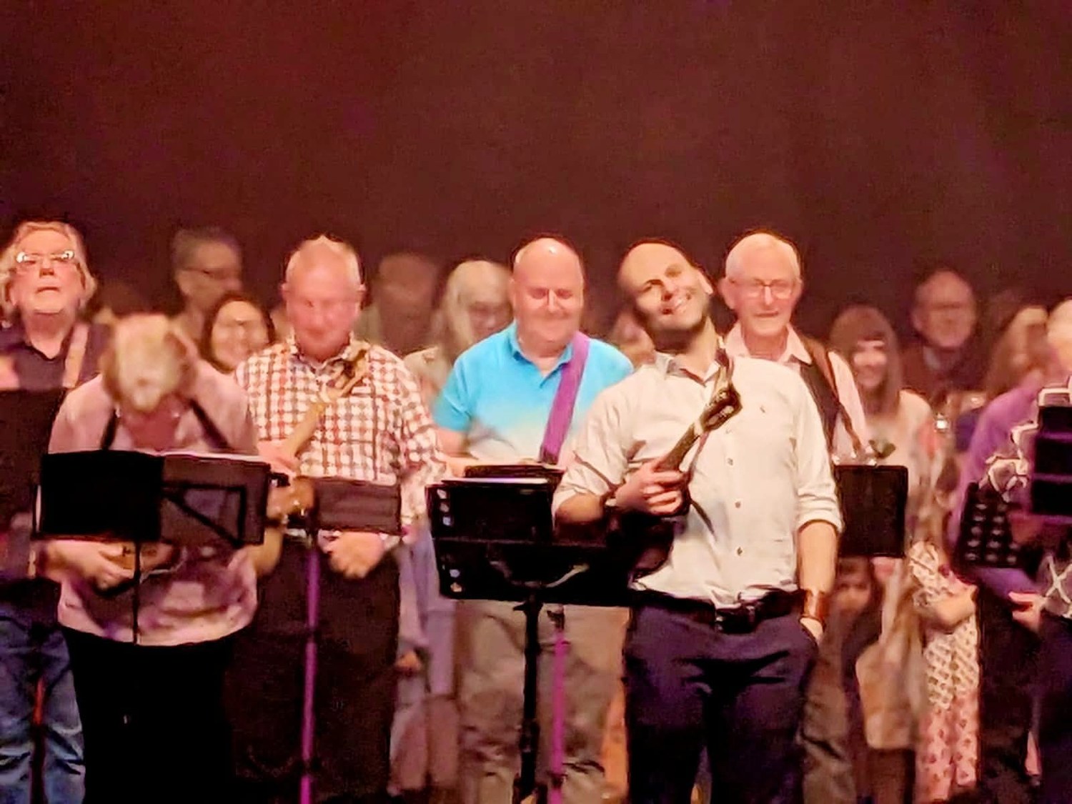 Adults playing instruments together on stage, smiling