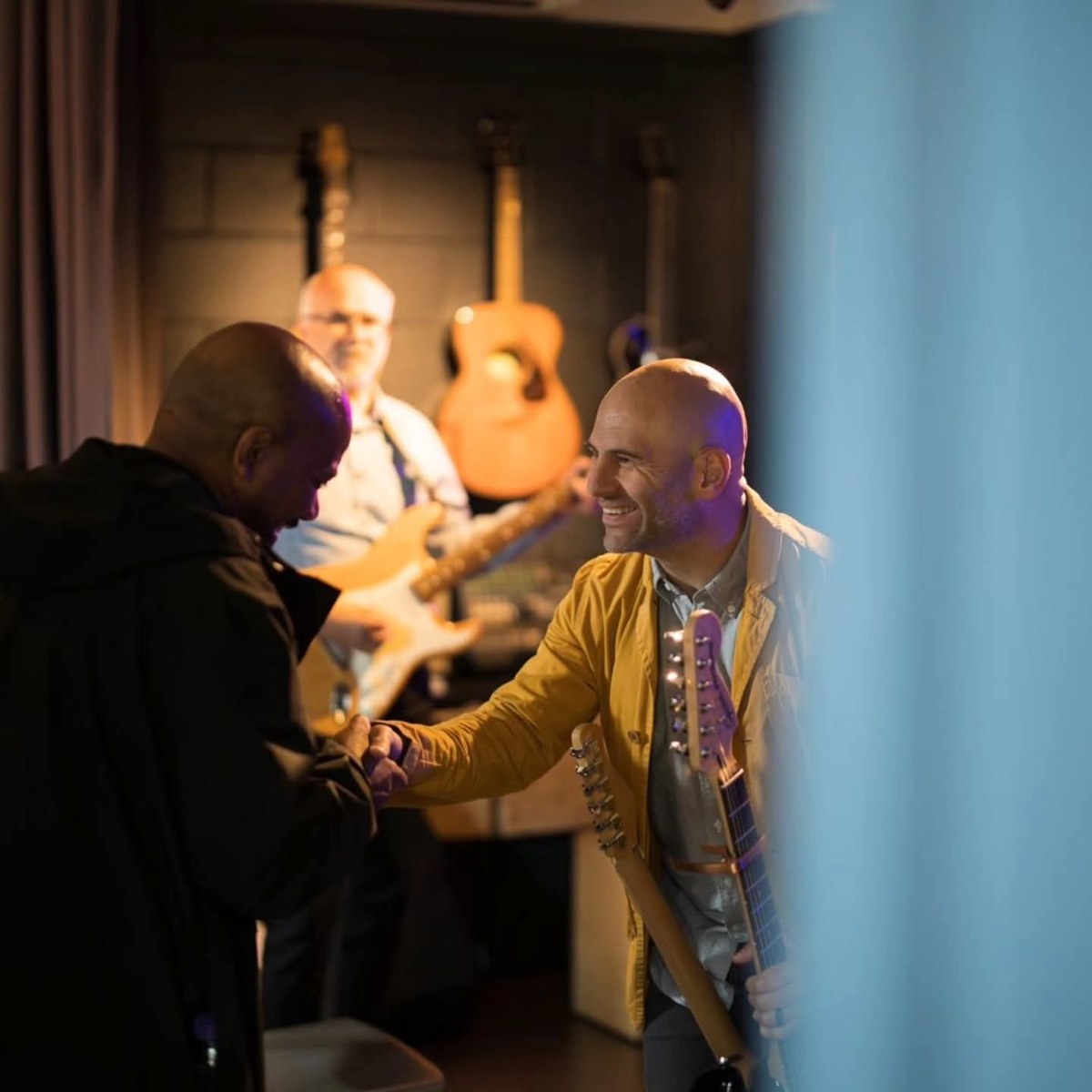 Barry warmly greeting someone with a handshake at a music gathering
