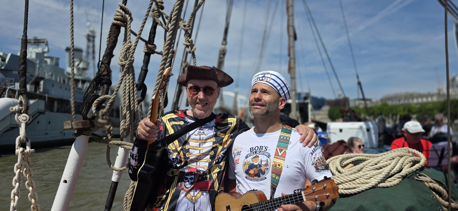 Barry de Jager with a ukulele aboard a traditional wooden sailing barge alongside fellow players